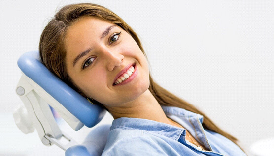 Dental patient with straight teeth reclined in treatment chair