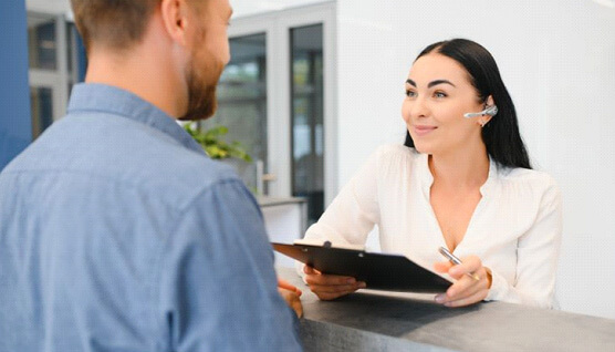 Patient and dental team member conversing at dental office front desk 