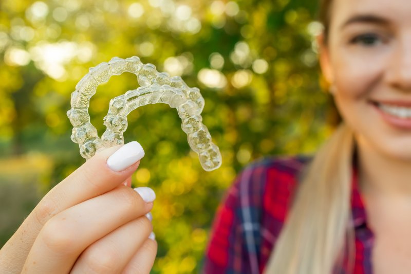 A teen girl holding two Angel Aligners in her hand